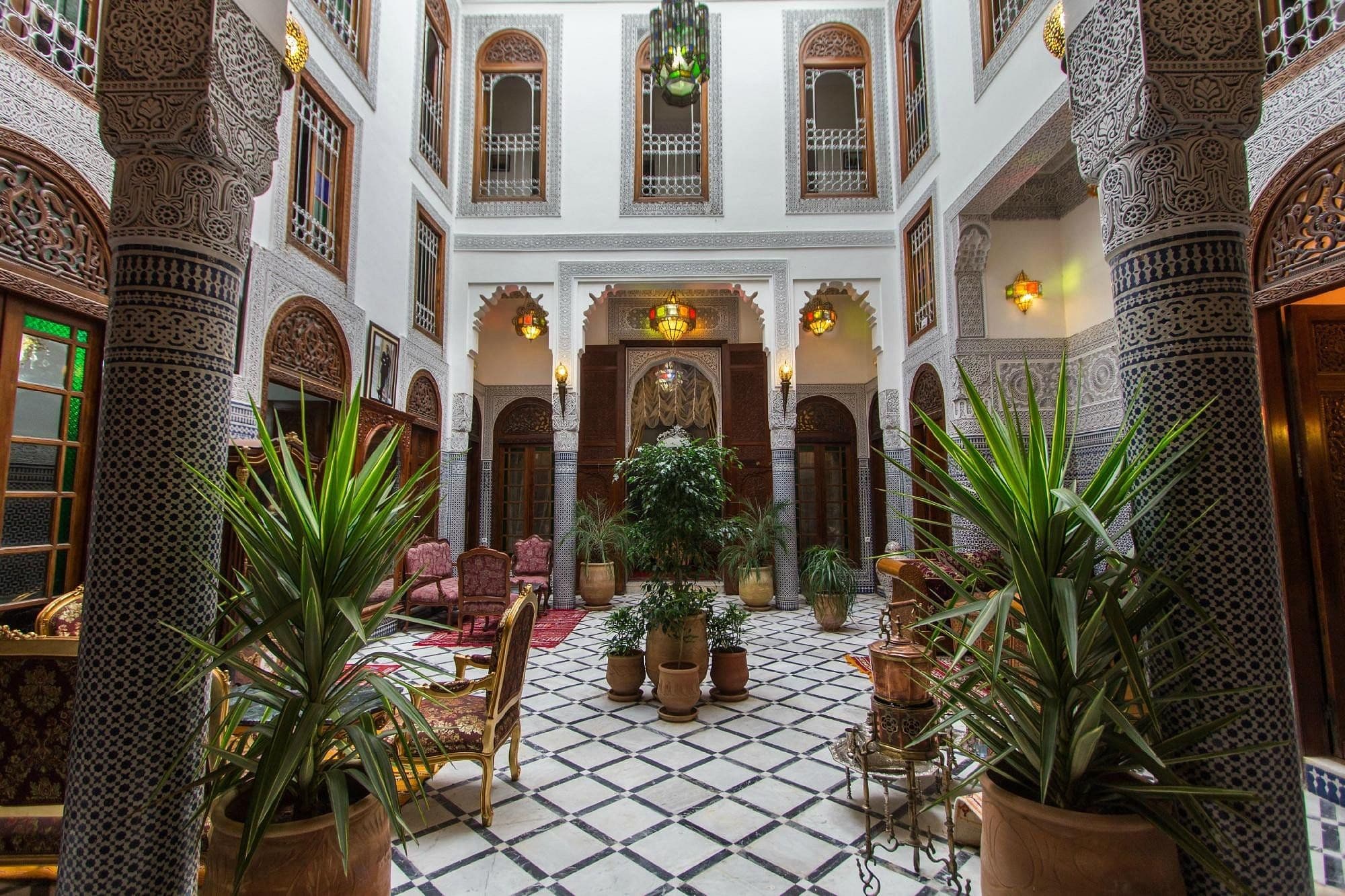 A quiet riad courtyard with palms and a patterned zellige floor